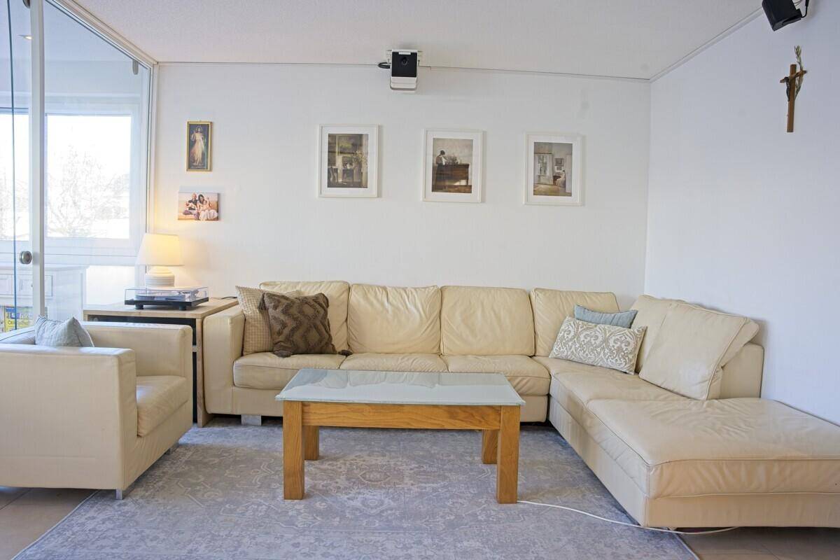 Gemütliches Wohnzimmer mit beigem Ecksofa, Couchtisch und heller, freundlicher Atmosphäre.