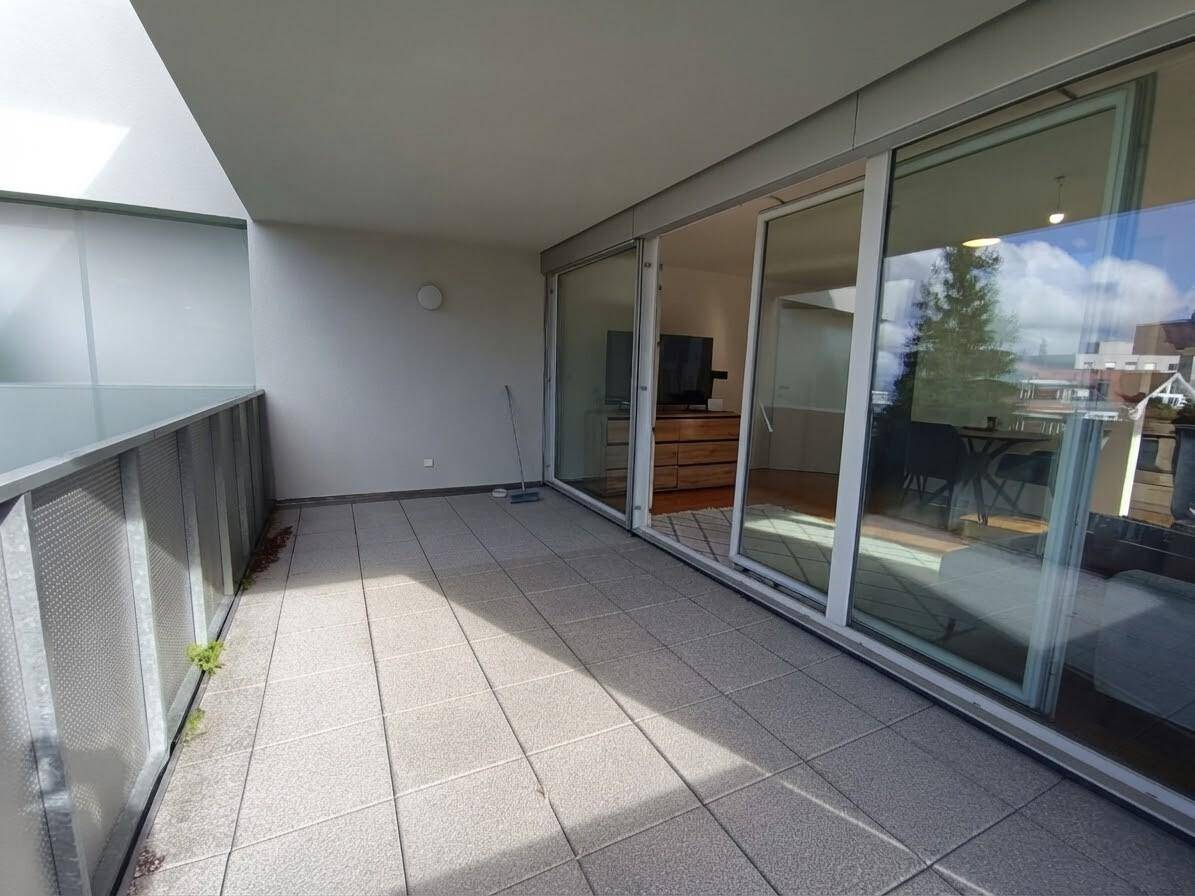 Geräumiger Balkon mit Fliesenboden und großen Glasschiebetüren, ideal zum Entspannen im Freien.