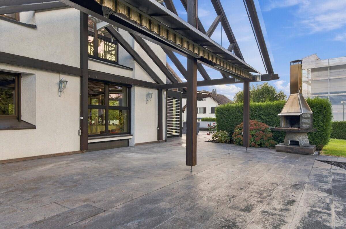 Weitläufige Terrasse mit festem Grill und Überdachung, ideal für gesellige Abende im Freien.