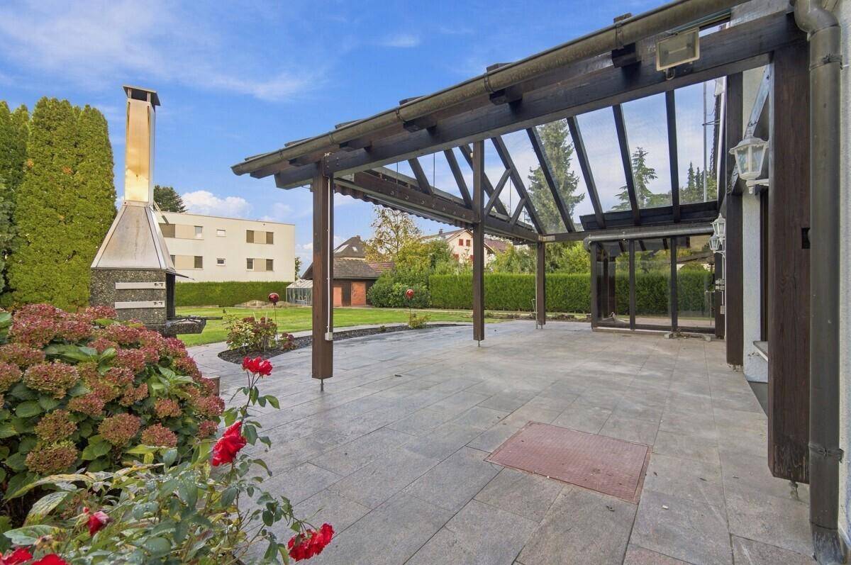 Große gepflasterte Terrasse mit Pergola, festem Grillplatz und weitem Blick ins Grüne.