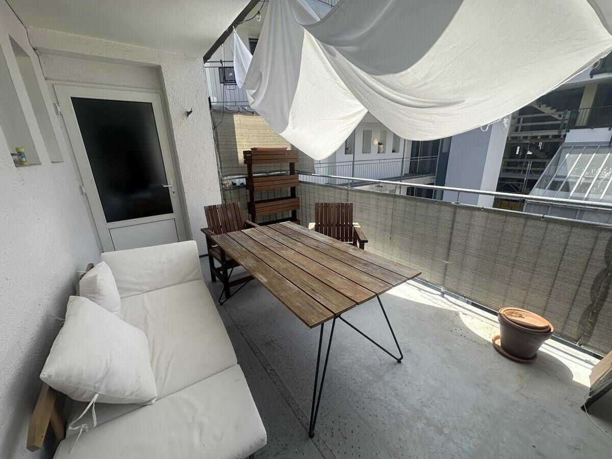 Gemütlicher Balkon mit Holztisch, Sitzgelegenheiten und Sonnenschutz für entspannte Stunden.