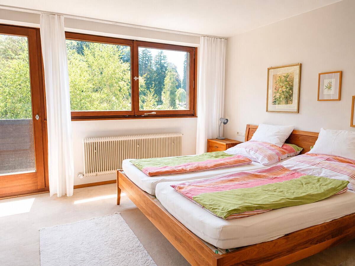Helles Schlafzimmer mit zwei Einzelbetten, Balkonzugang und Blick ins Grüne.