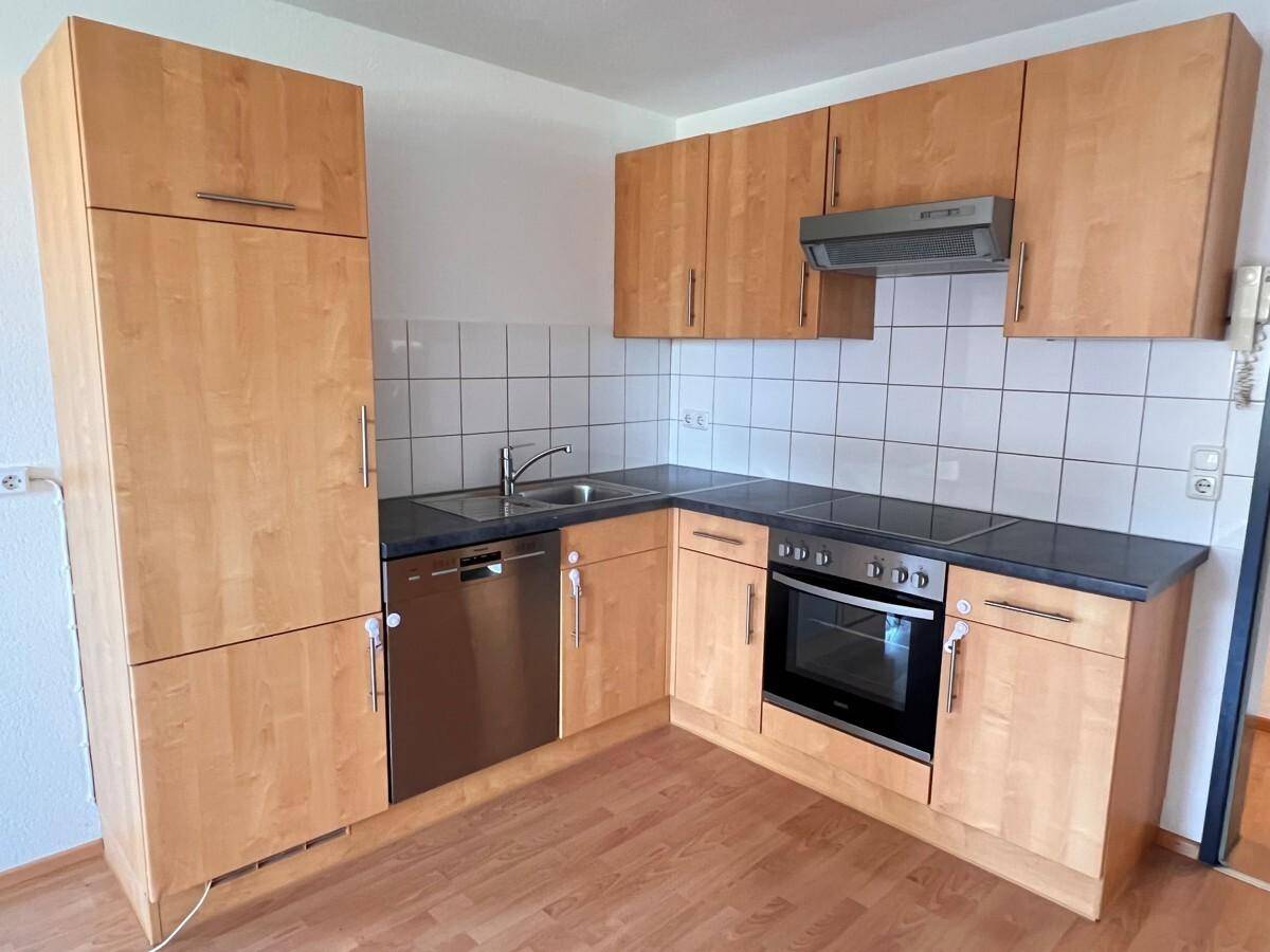 Funktionale Einbauküche mit Holzfronten, modernen Geräten und Fliesenrückwand.