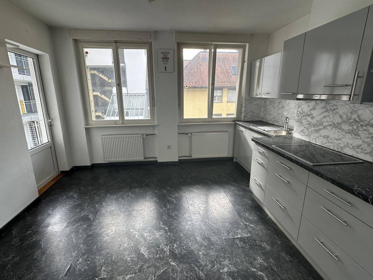 Küche mit grauen Schränken, dunkler Arbeitsplatte und Fensterblick, bereit zur Fertigstellung.