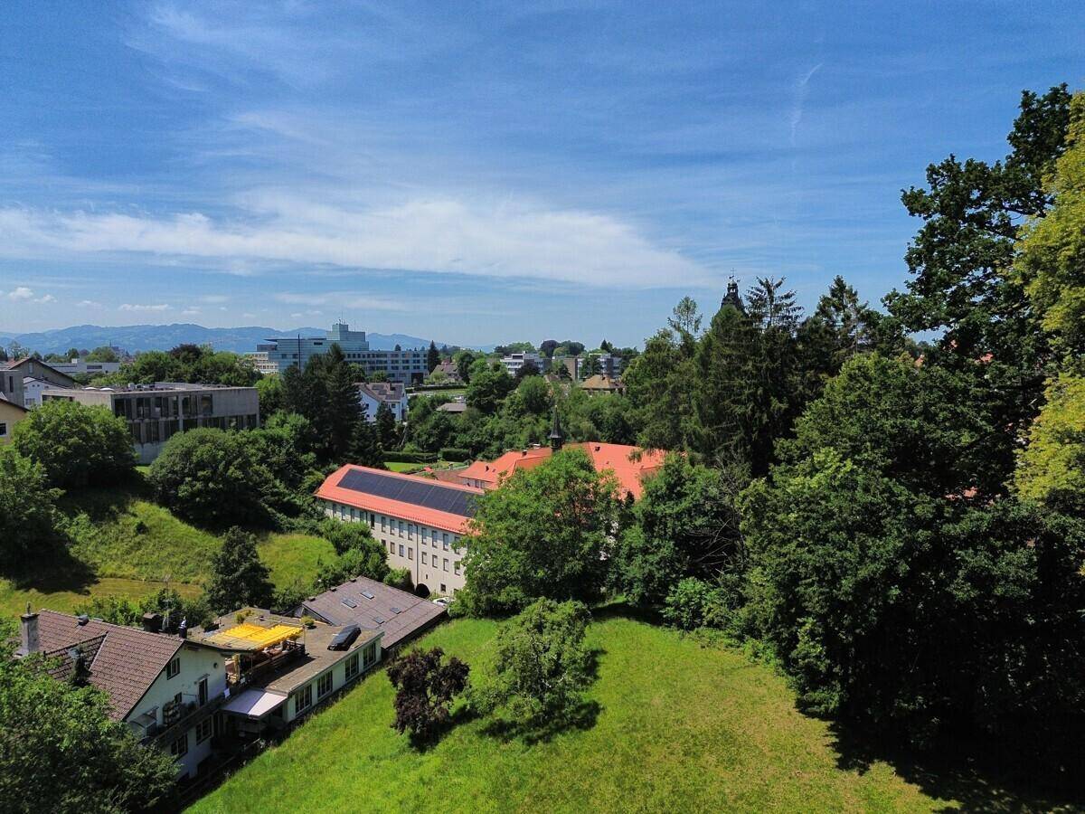 Weitläufige Luftaufnahme der Umgebung mit Häusern, Bäumen und einem Gebäude mit Solaranlage.
