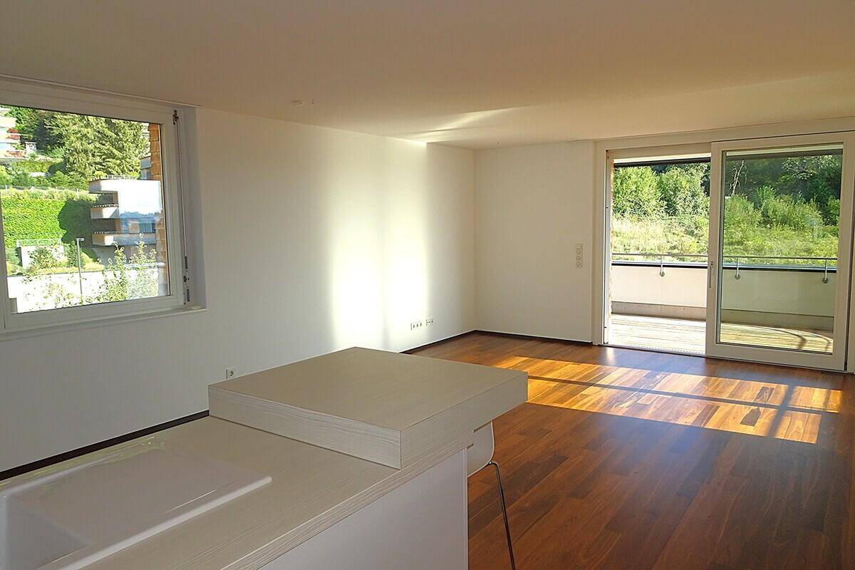 Helles Wohnzimmer mit Holzboden, großen Fenstern und direktem Zugang zu einem sonnigen Balkon.