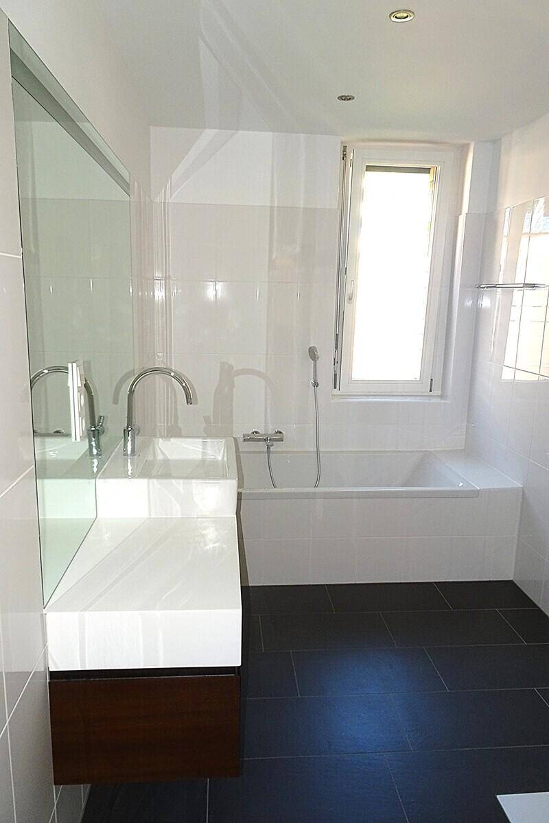 Modernes Badezimmer mit Badewanne, elegantem Waschtisch und einem Fenster für Tageslicht.