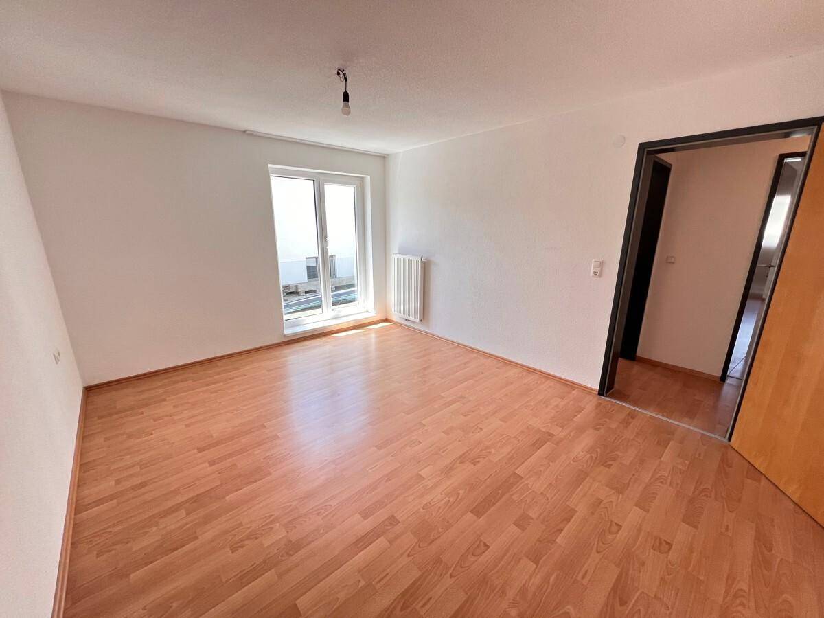 Geräumiges Zimmer mit Holzboden und Balkonzugang, ideal als Schlaf- oder Arbeitszimmer.