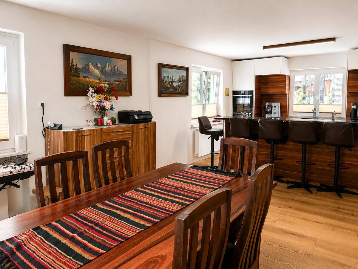 Geräumiger Essbereich mit Holztisch und offener Verbindung zur modernen Küche mit Barhockern.