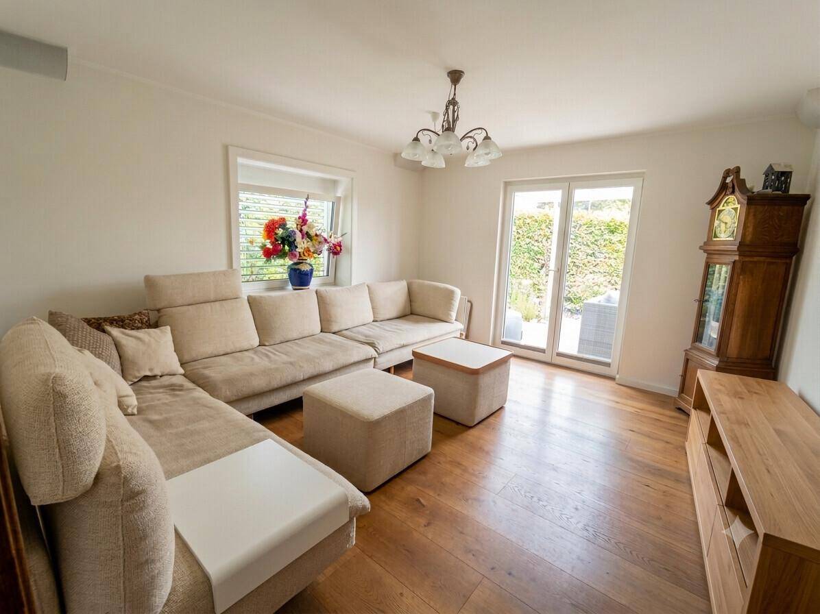 Gemütliches Wohnzimmer mit großem Sofa, Holzboden und direktem Zugang zur Terrasse oder Garten.