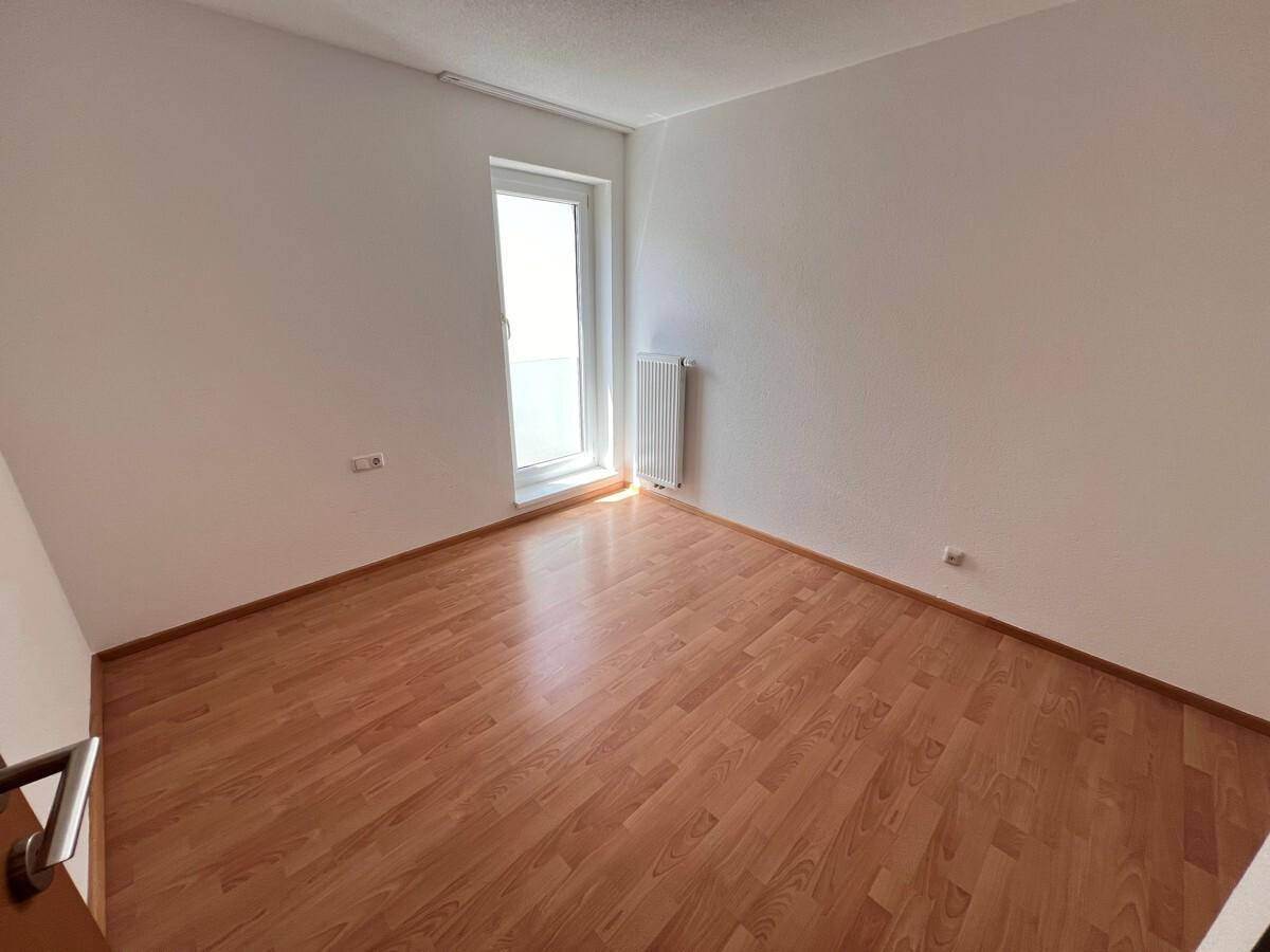 Freundliches Zimmer mit Holzboden und Zugang zu einem möglichen Balkon oder Terrasse.