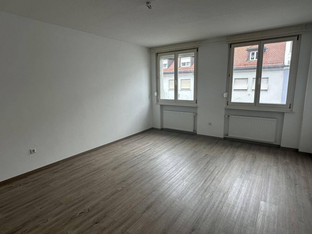 Heller, leerer Raum mit Laminatboden und zwei Fenstern, ideal für Schlaf- oder Wohnbereich.