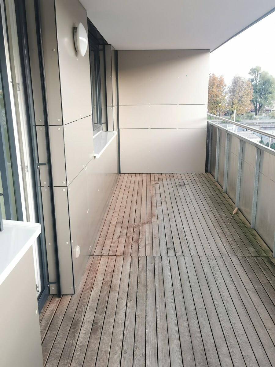 Geräumiger Balkon mit Holzdielenboden und Metallgeländer, ideal für entspannte Stunden im Freien.