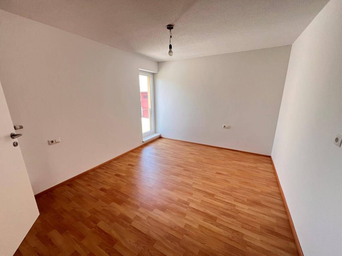 Helles Zimmer mit Holzboden und Fenster, geeignet als Kinder- oder Gästezimmer.