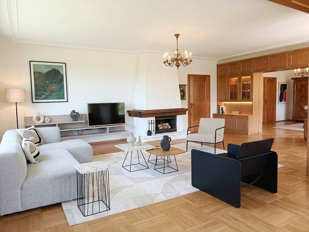 Modernisiertes Wohnzimmer mit Kamin, hellem Sofa und Parkettboden, einladend und stilvoll.