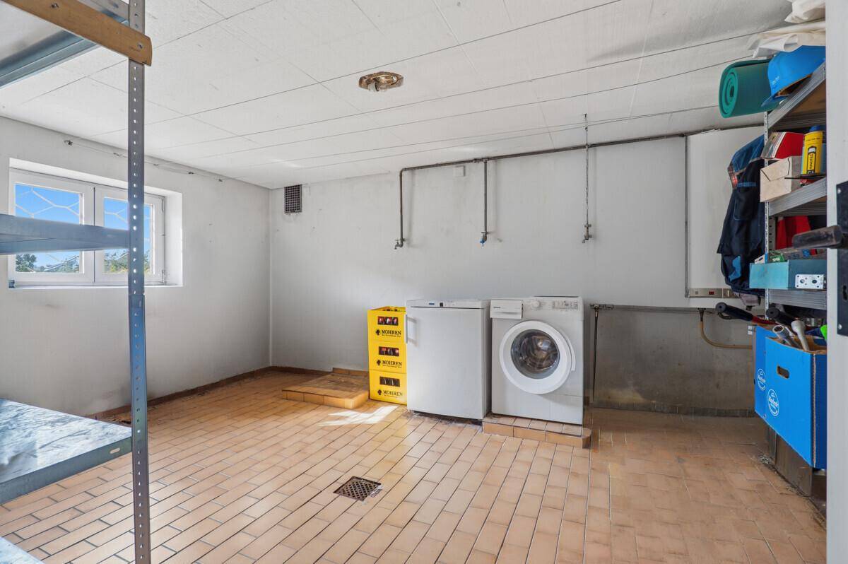 Hauswirtschaftsraum im Keller mit Waschmaschine, Trockner und praktischen Lagerregalen.