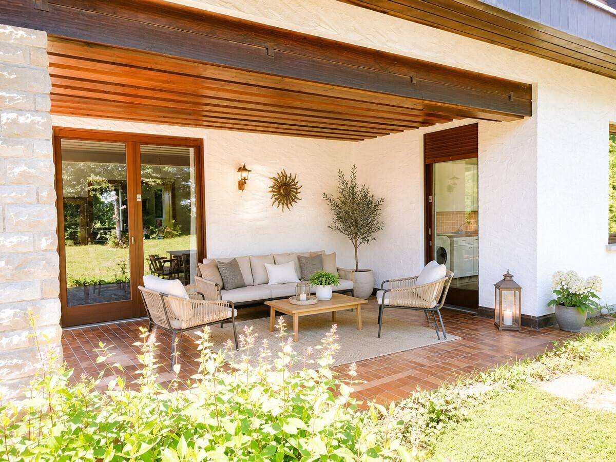 Überdachte Terrasse mit bequemen Gartenmöbeln und Blick auf den gepflegten Garten.