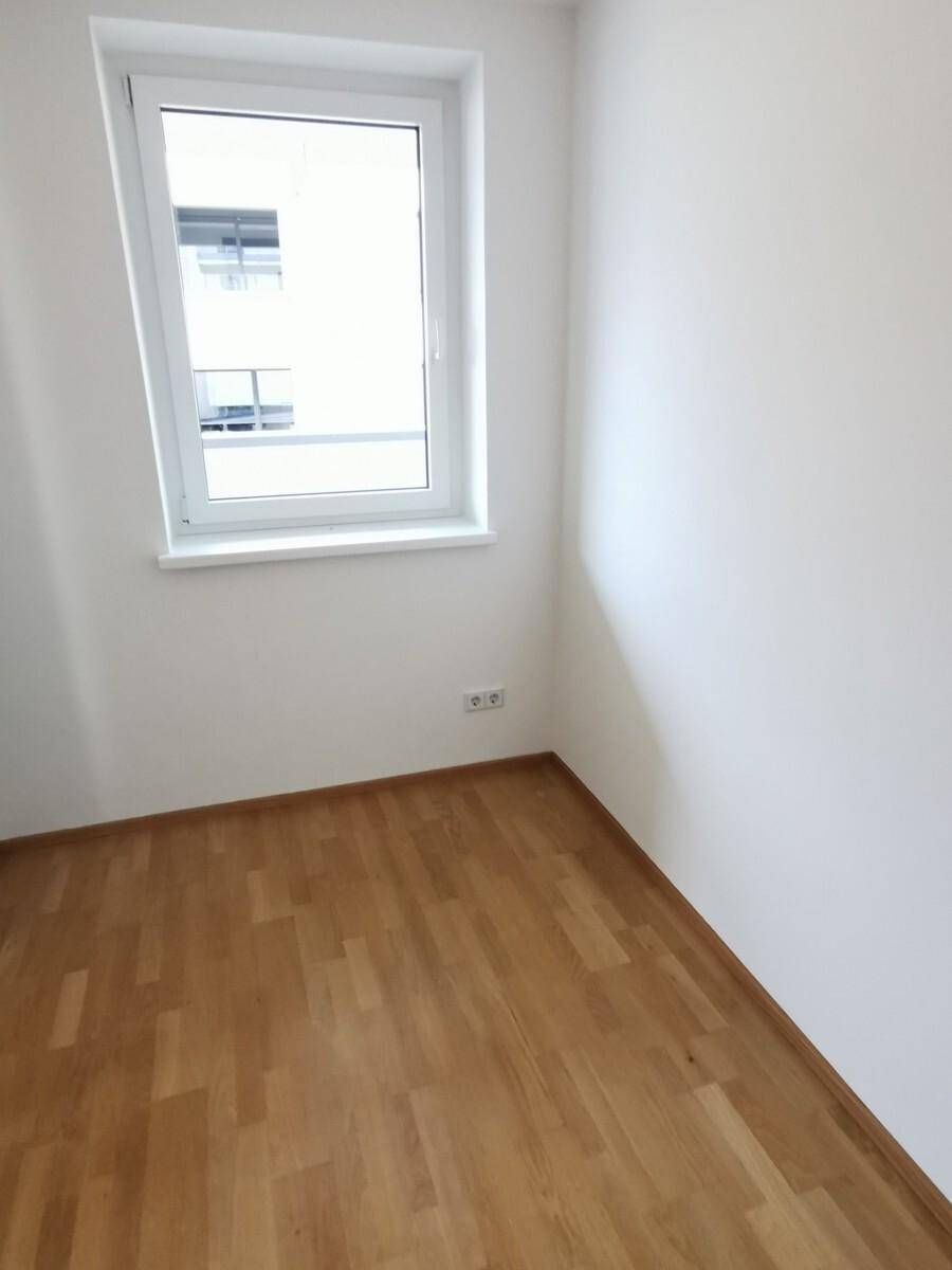 Kleineres Zimmer mit Parkettboden und einem Fenster, ideal als Kinder- oder Arbeitszimmer.