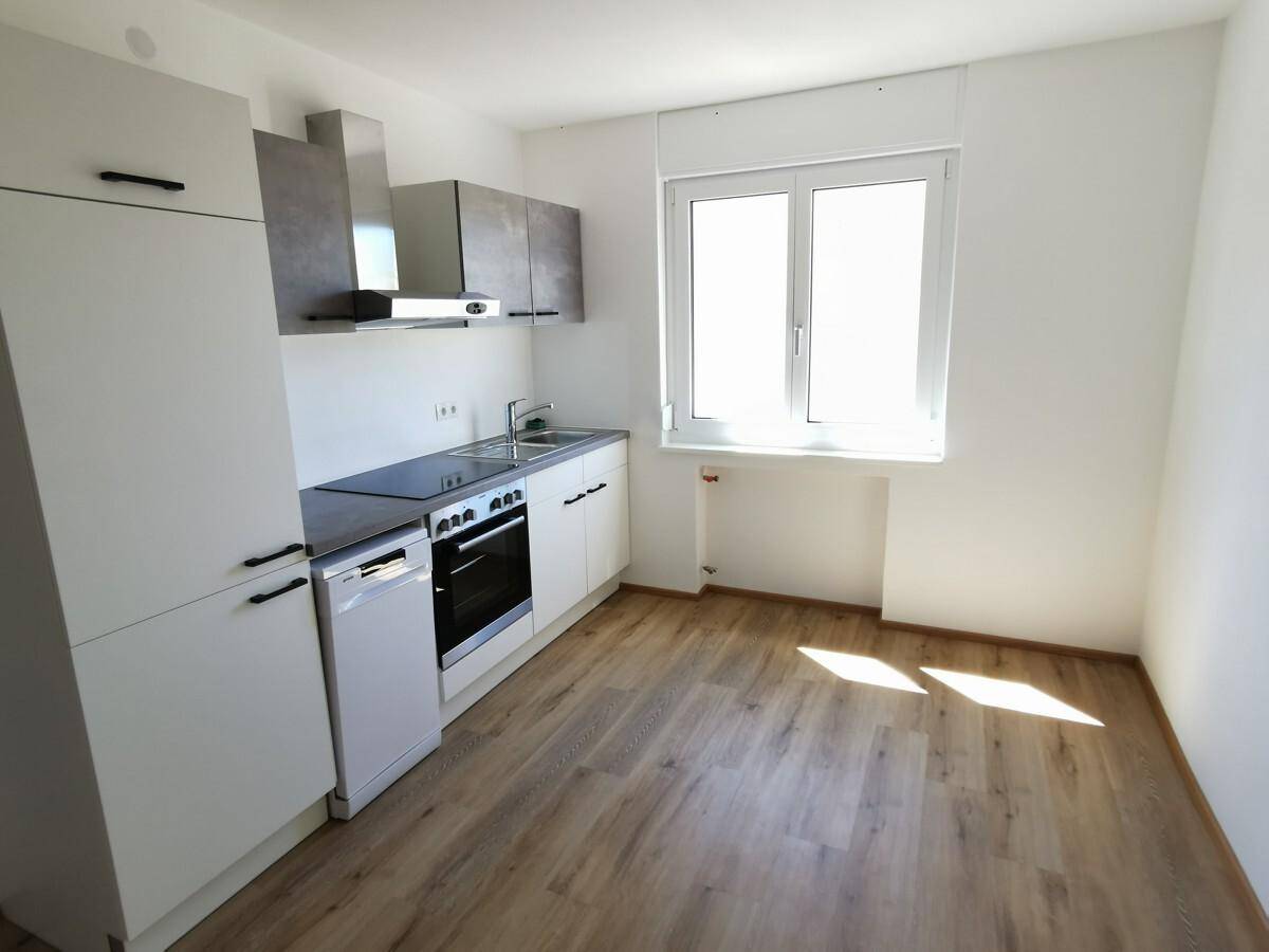 Moderne, helle Küche mit neuen Einbauschränken, Spüle, Ofen und Geschirrspüler.
