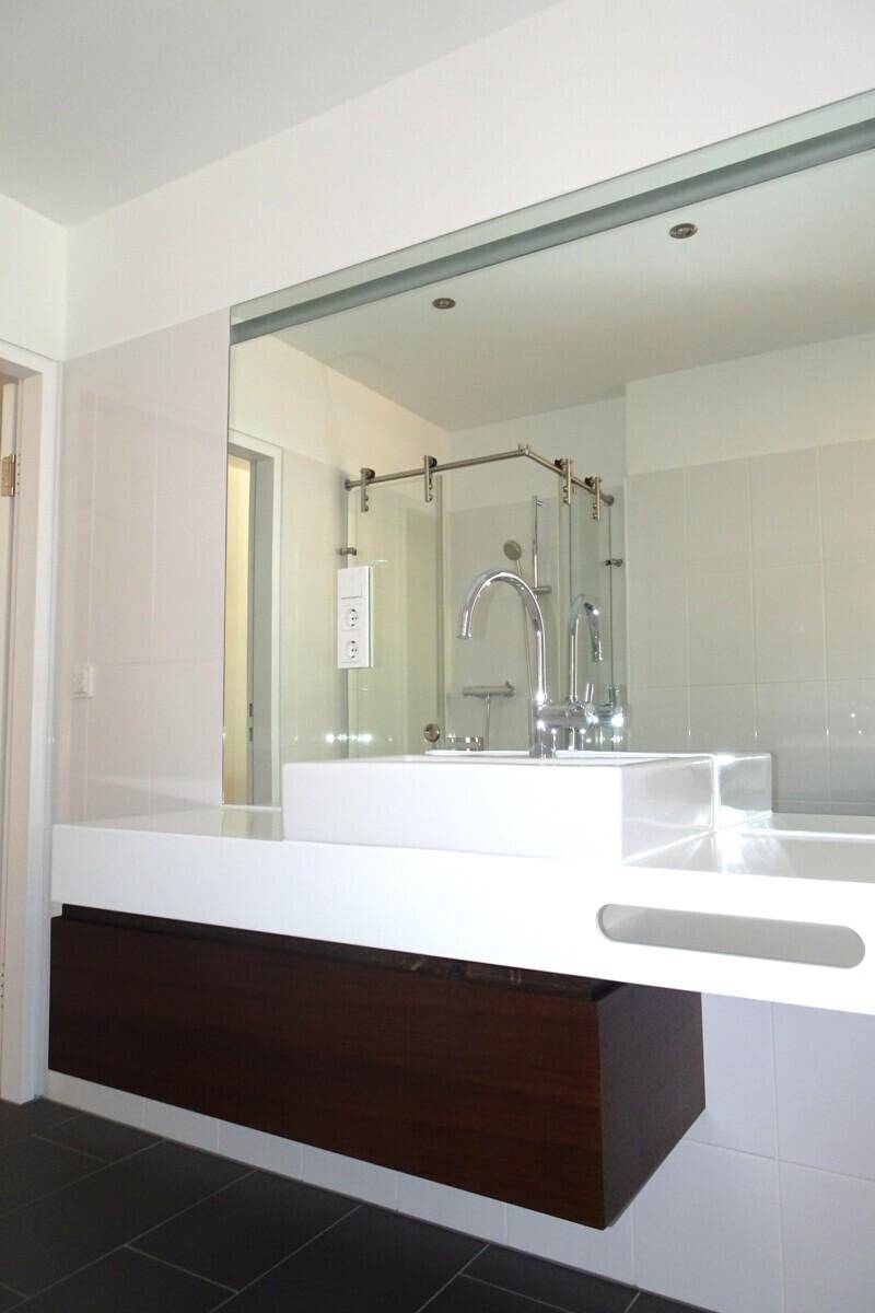 Moderner Waschtisch mit großem Spiegel und eleganten Armaturen in einem hellen Badezimmer.