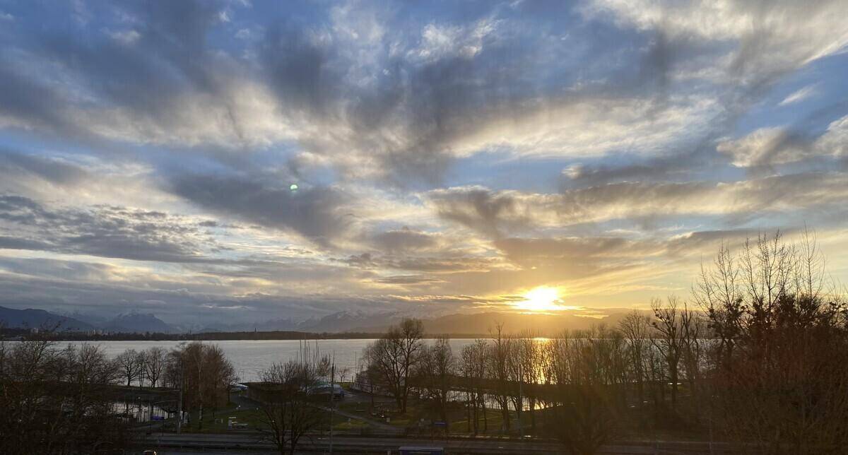 Malerischer Sonnenuntergang über einem See mit Bergen im Hintergrund, eine atemberaubende Aussicht.
