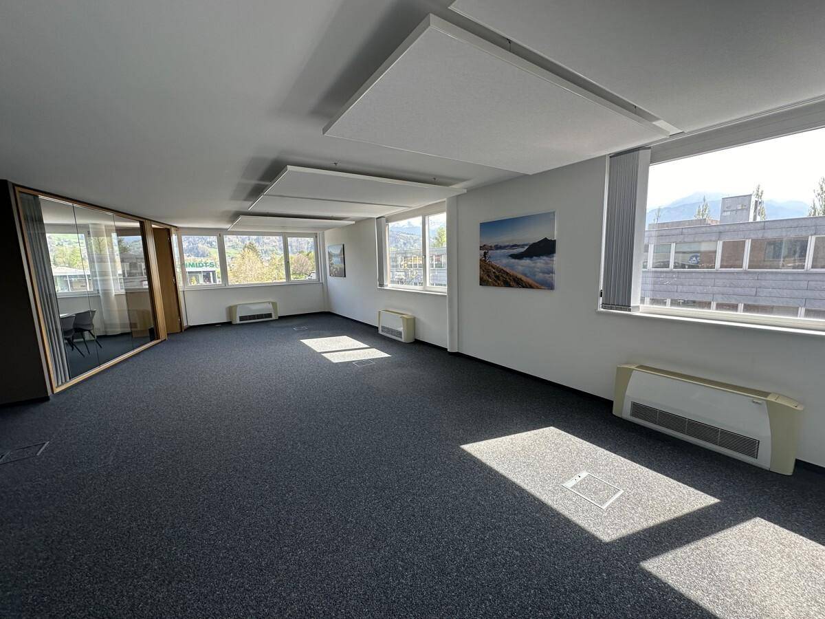 Geräumiger, offener Bürobereich mit Teppichboden, großen Fenstern und viel Tageslicht.