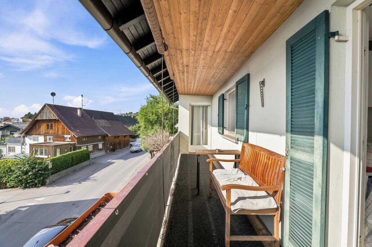 Balkon mit Holzbank und Blick auf die Straße, ideal für entspannte Stunden im Freien.