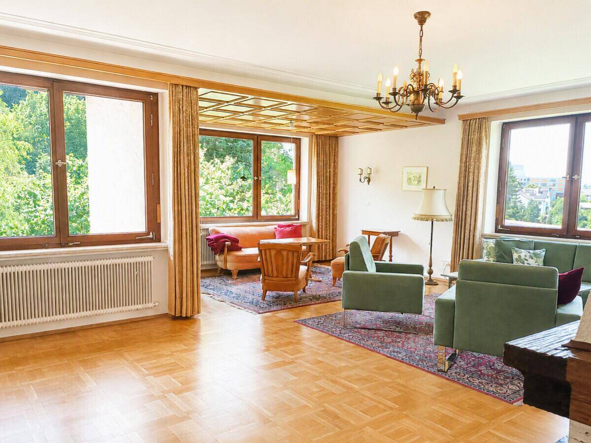 Geräumiges Wohnzimmer mit Holzbalkendecke, großen Fenstern und traditioneller Einrichtung.