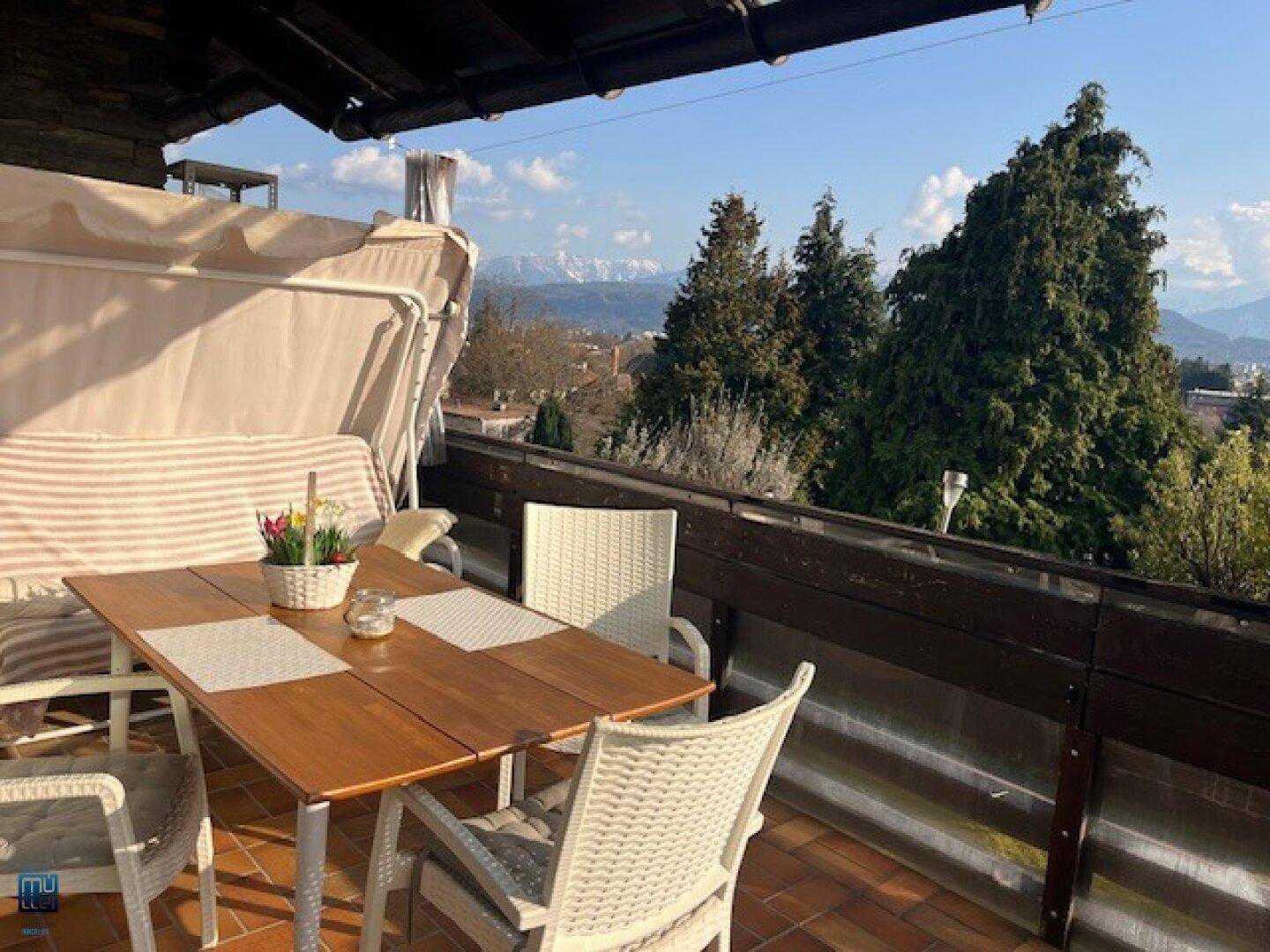 Gemütlicher Balkon mit Sitzgelegenheiten, Markise und einem weiten Blick auf die umliegende Berglandschaft.