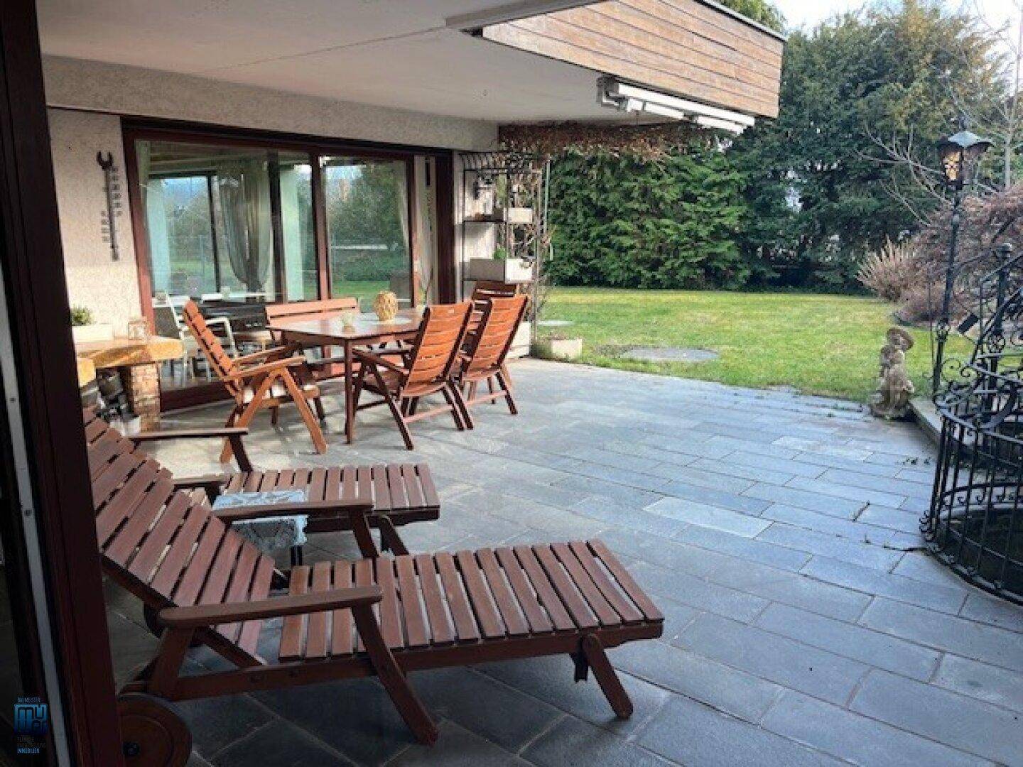 Geräumige Terrasse mit Liegestühlen, Essbereich und einem schönen Blick auf den grünen Garten.
