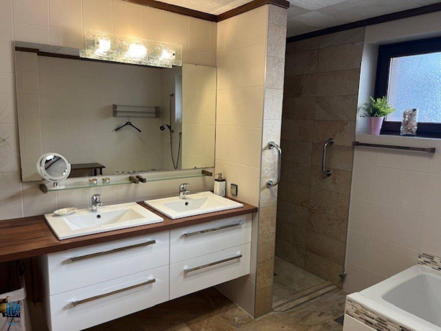 Modernes Badezimmer mit Doppelwaschbecken, großer Spiegelfläche und einer begehbaren Dusche.
