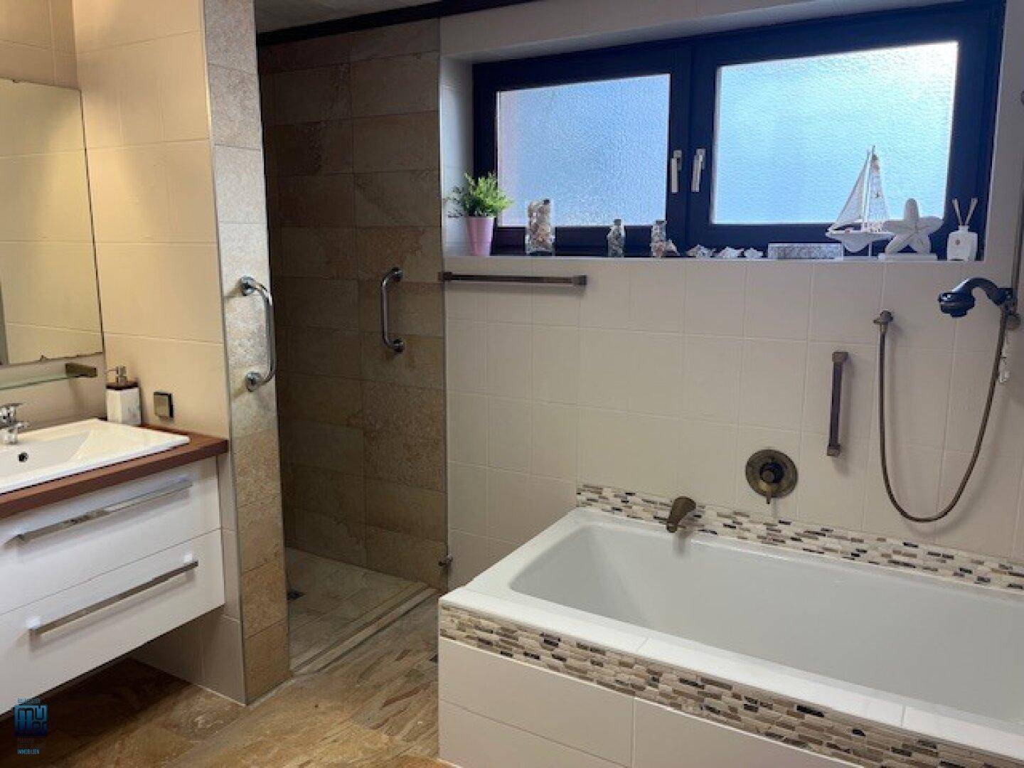 Helles Badezimmer mit Badewanne, Dusche und einem Fenster für natürliches Licht und Belüftung.