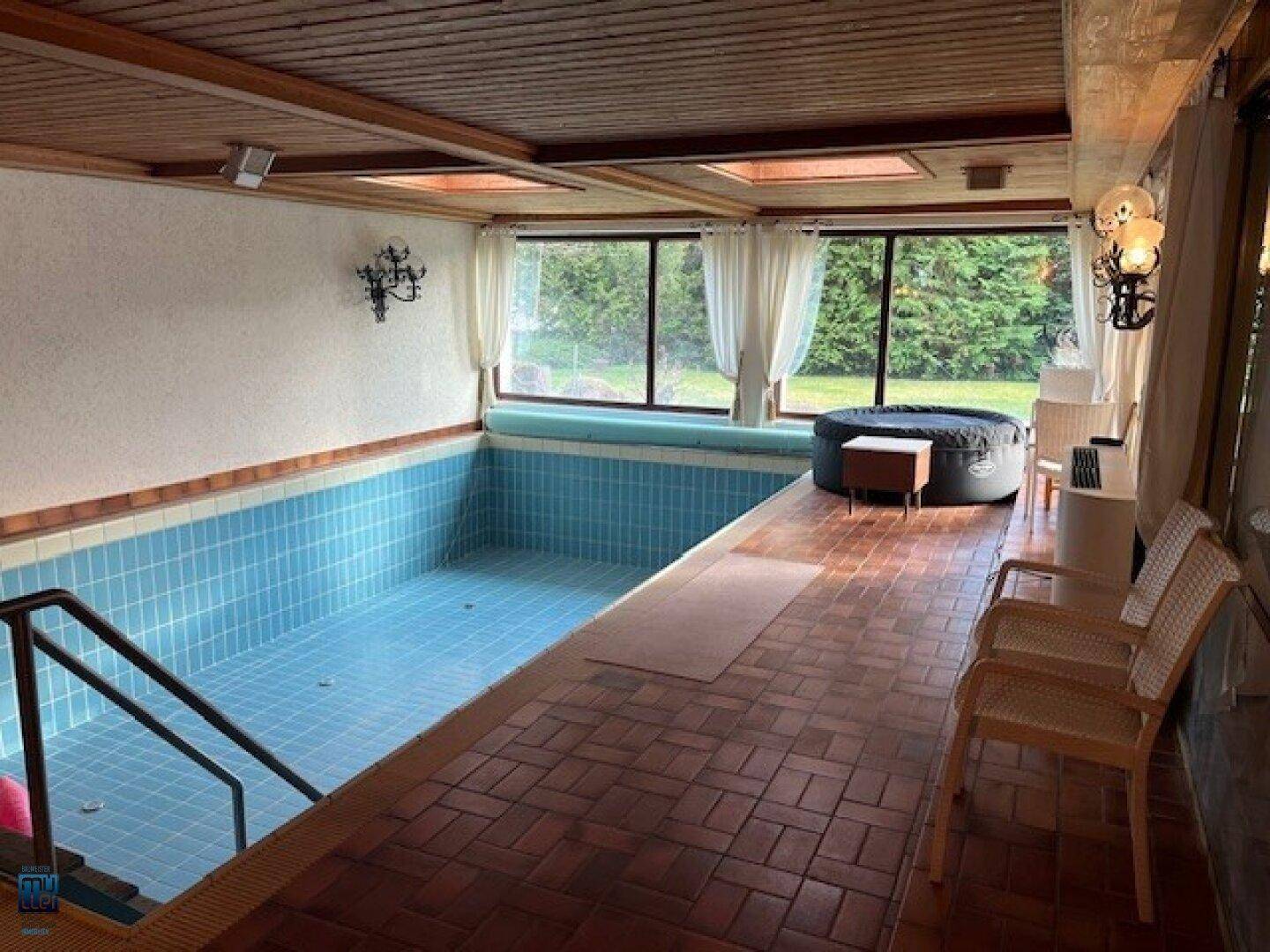 Heller Innenpoolbereich mit Fliesenboden, großen Fenstern und einem zusätzlichen Whirlpool.