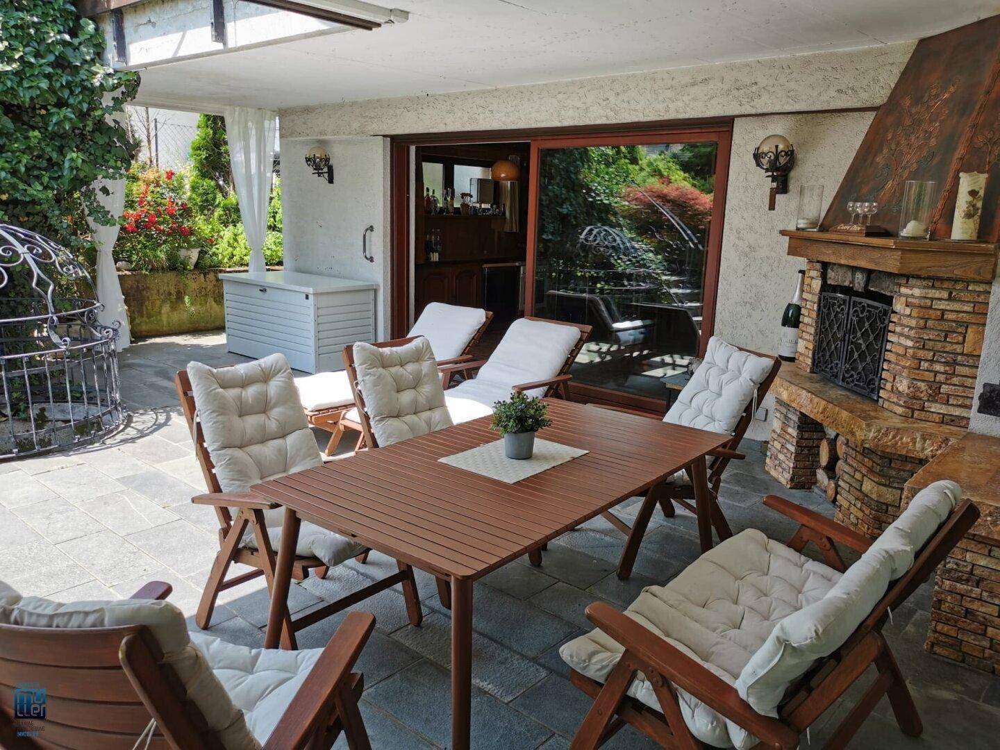Überdachte Terrasse mit Essbereich, gemauertem Kamin und direktem Zugang zum Garten.
