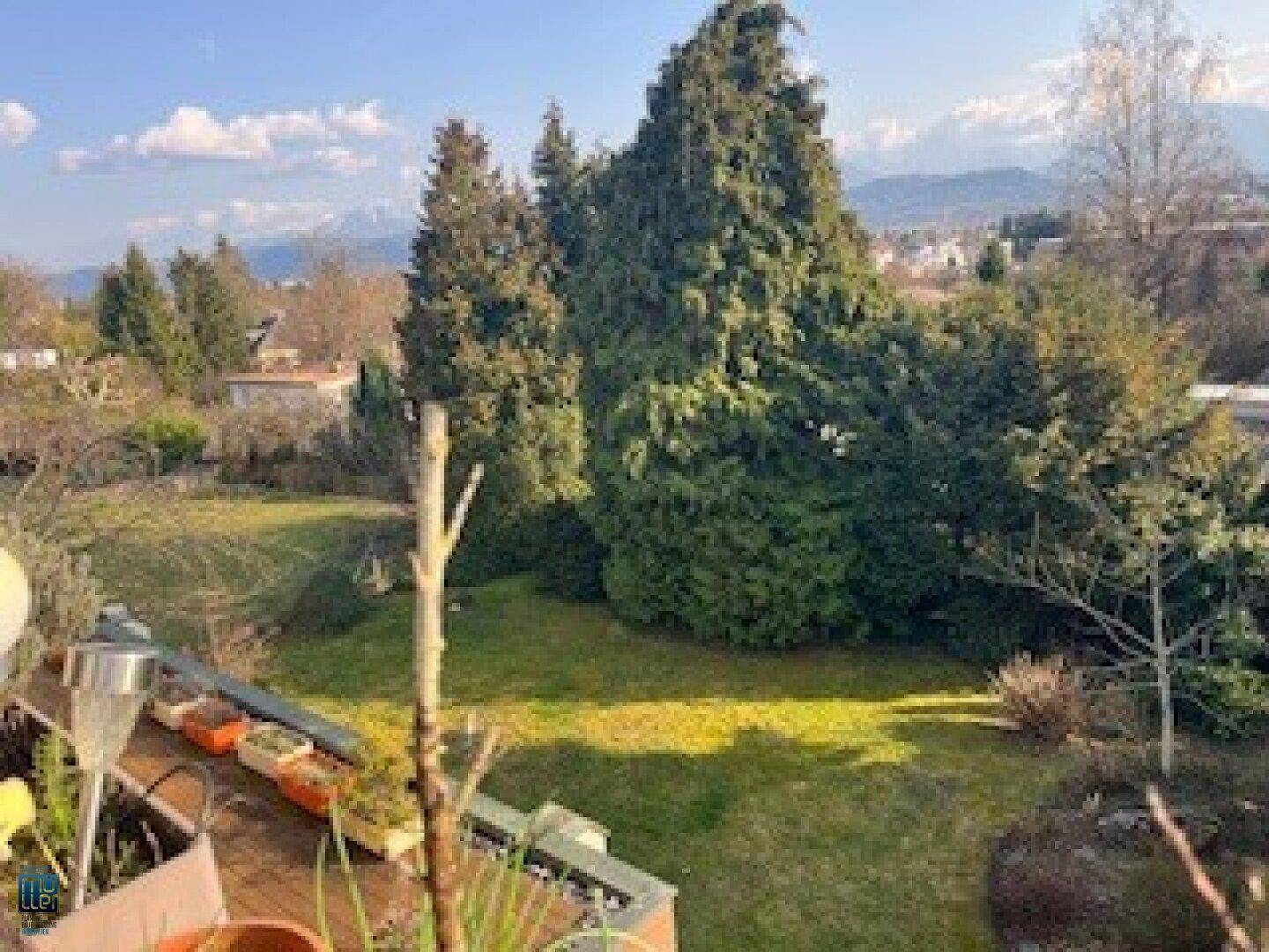 Gepflegter Gartenbereich mit weitläufiger Rasenfläche und hohen Bäumen, umgeben von Natur.
