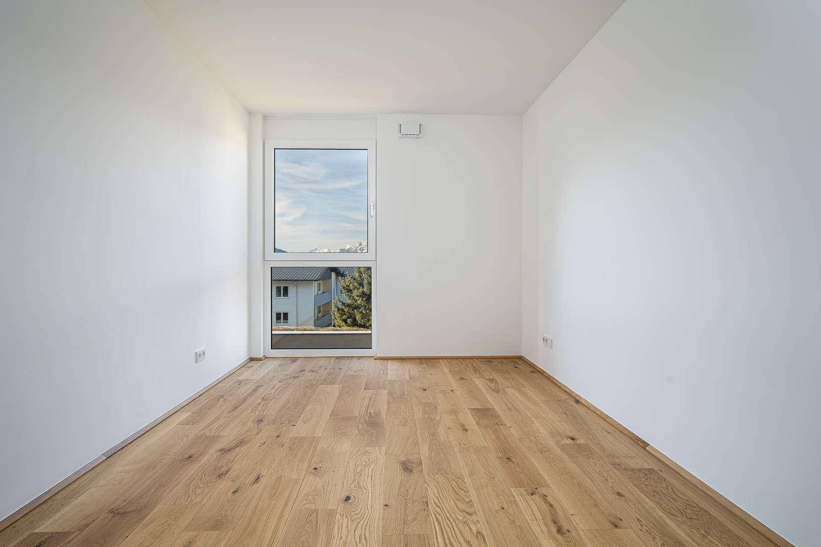 Weiteres Schlafzimmer mit Eichenparkett und großem Fenster für viel Tageslicht.