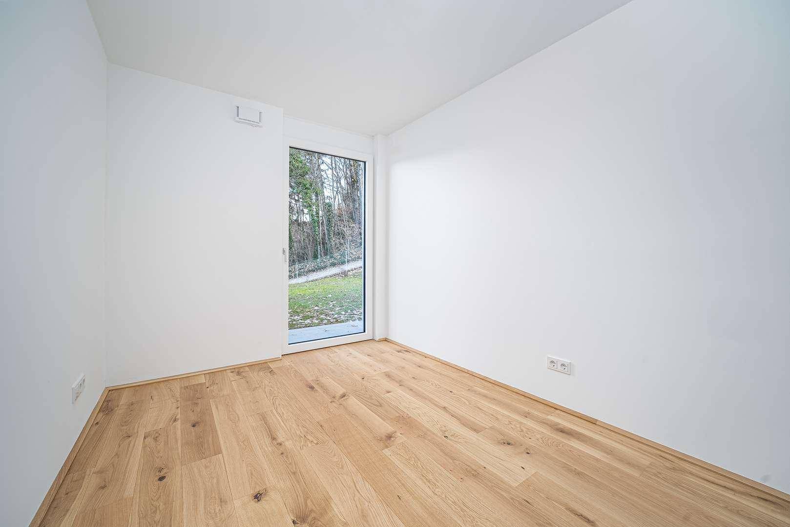 Helles Schlafzimmer mit Holzboden und Zugang zum Garten, ideal für Ruhe und Entspannung.