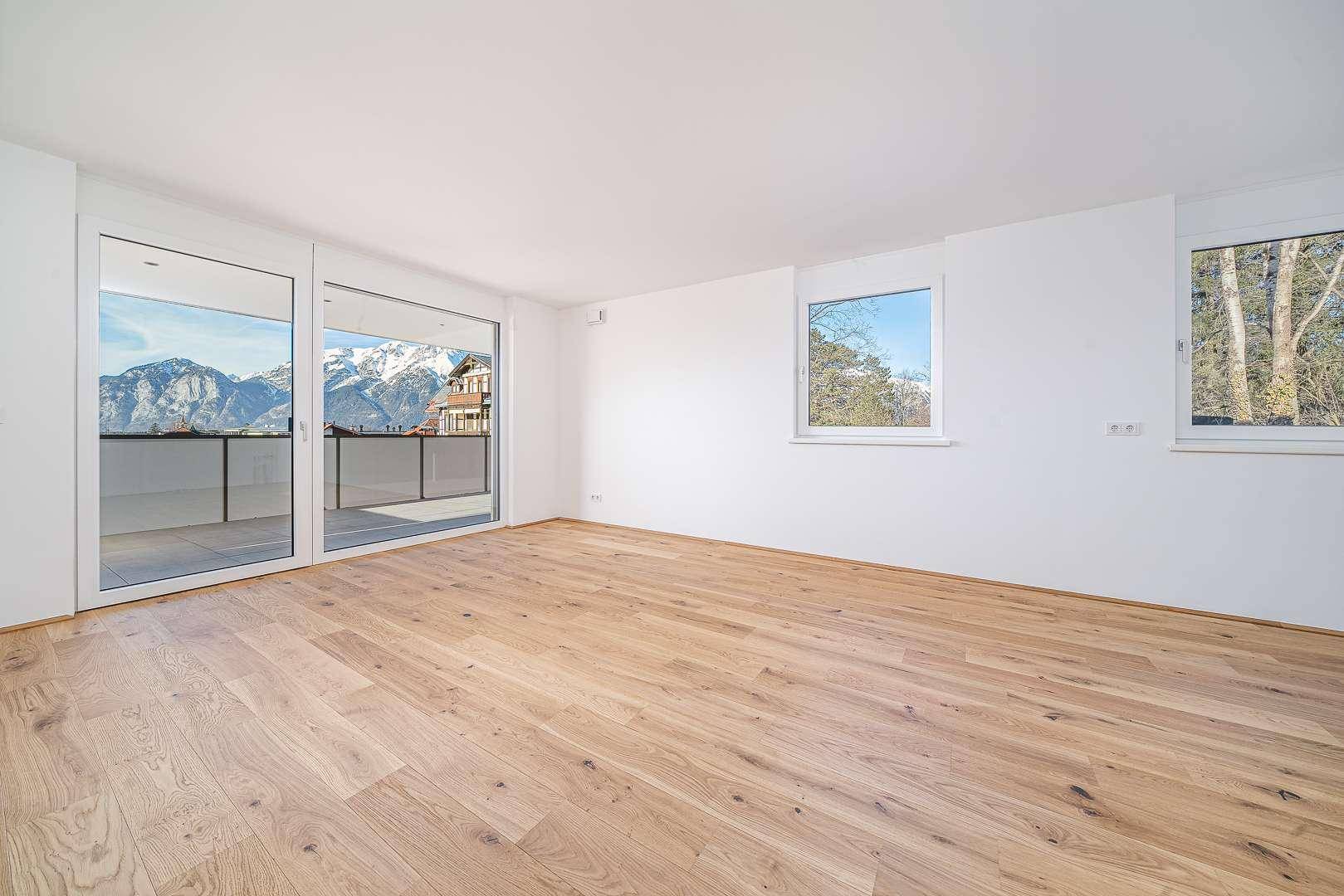 Helles Wohnzimmer mit Eichenparkett und großen Fenstern mit beeindruckendem Bergblick.