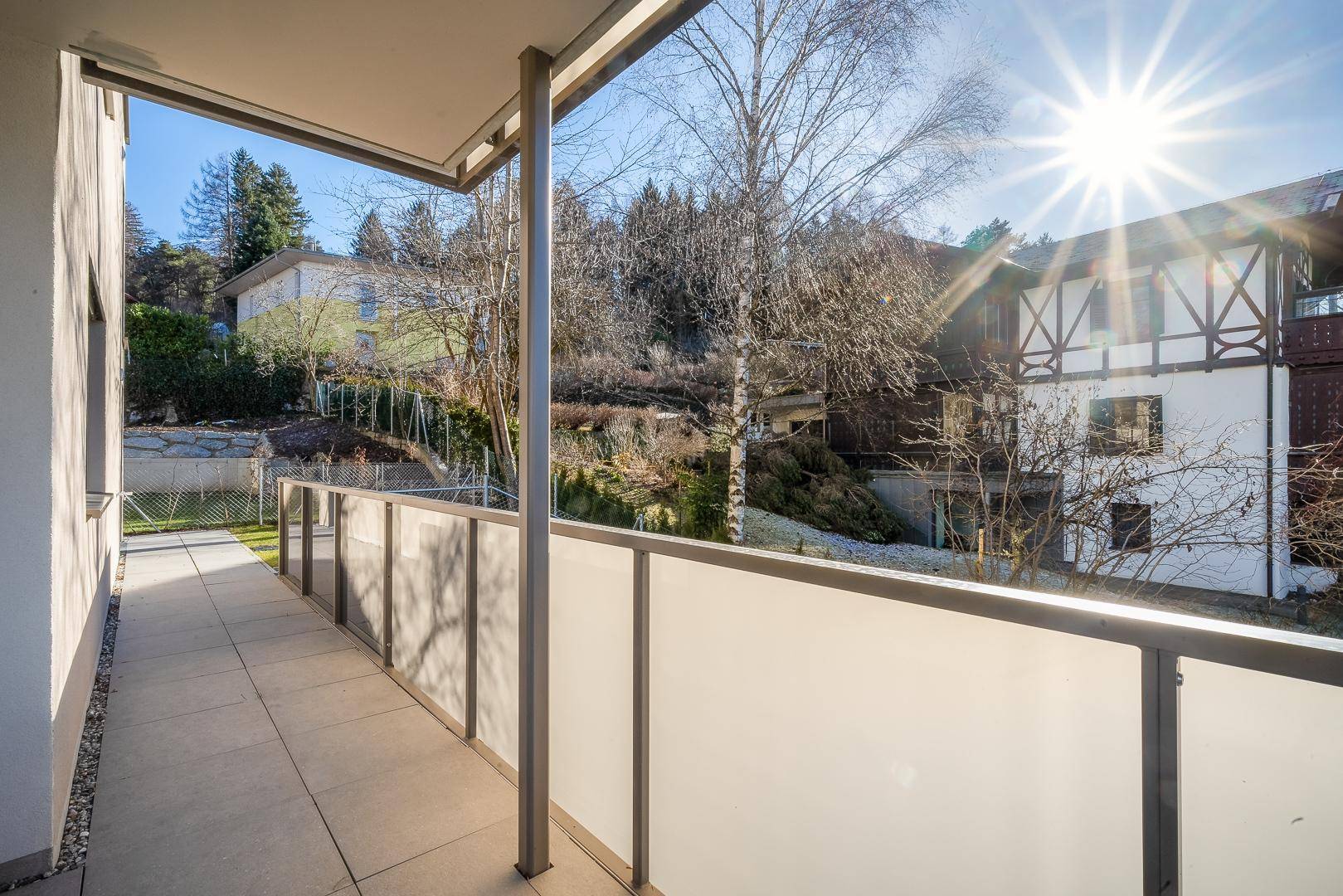 Sonniger Balkon mit Fliesenboden und Blick ins Grüne, ideal zum Entspannen.