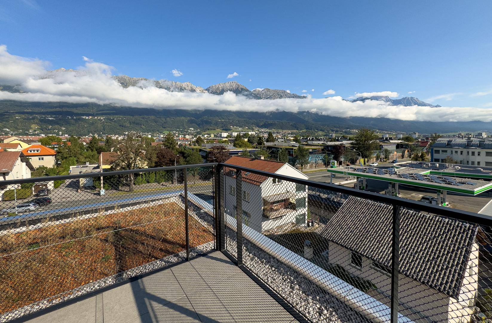 Dachterrasse mit Fliesenboden und Panoramablick auf die Stadt und die majestätischen Berge.