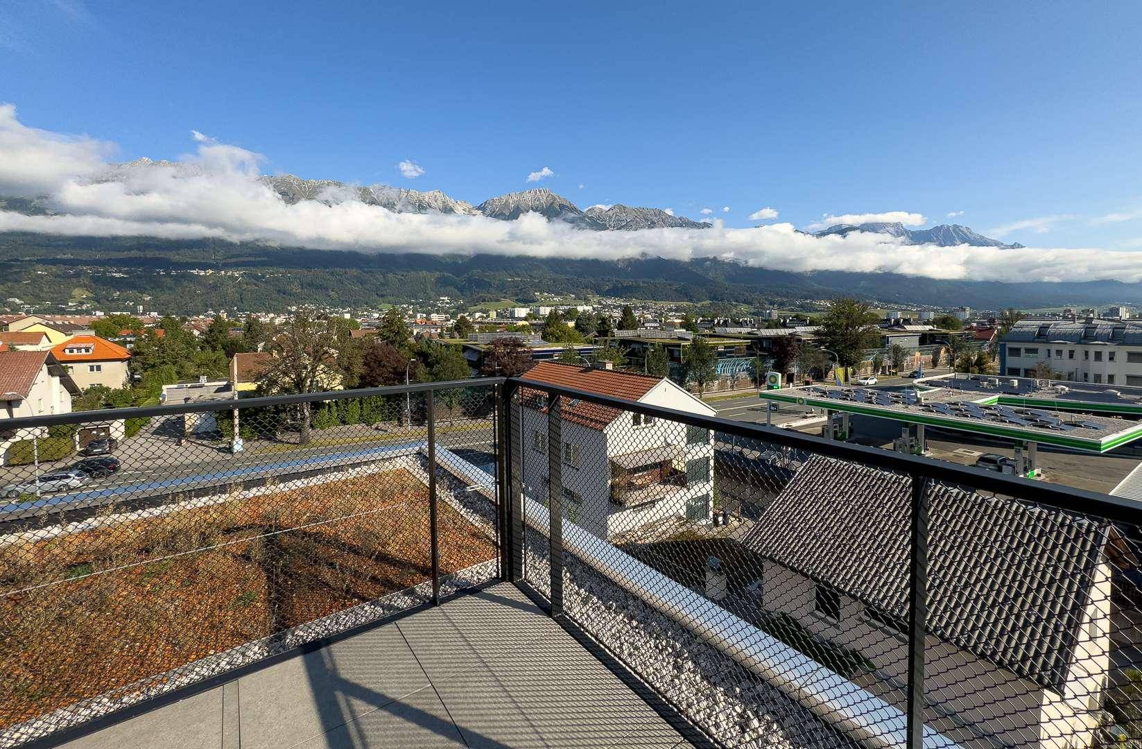 Balkon mit Gittergeländer und Panoramablick auf die Stadt und die majestätischen Berge.