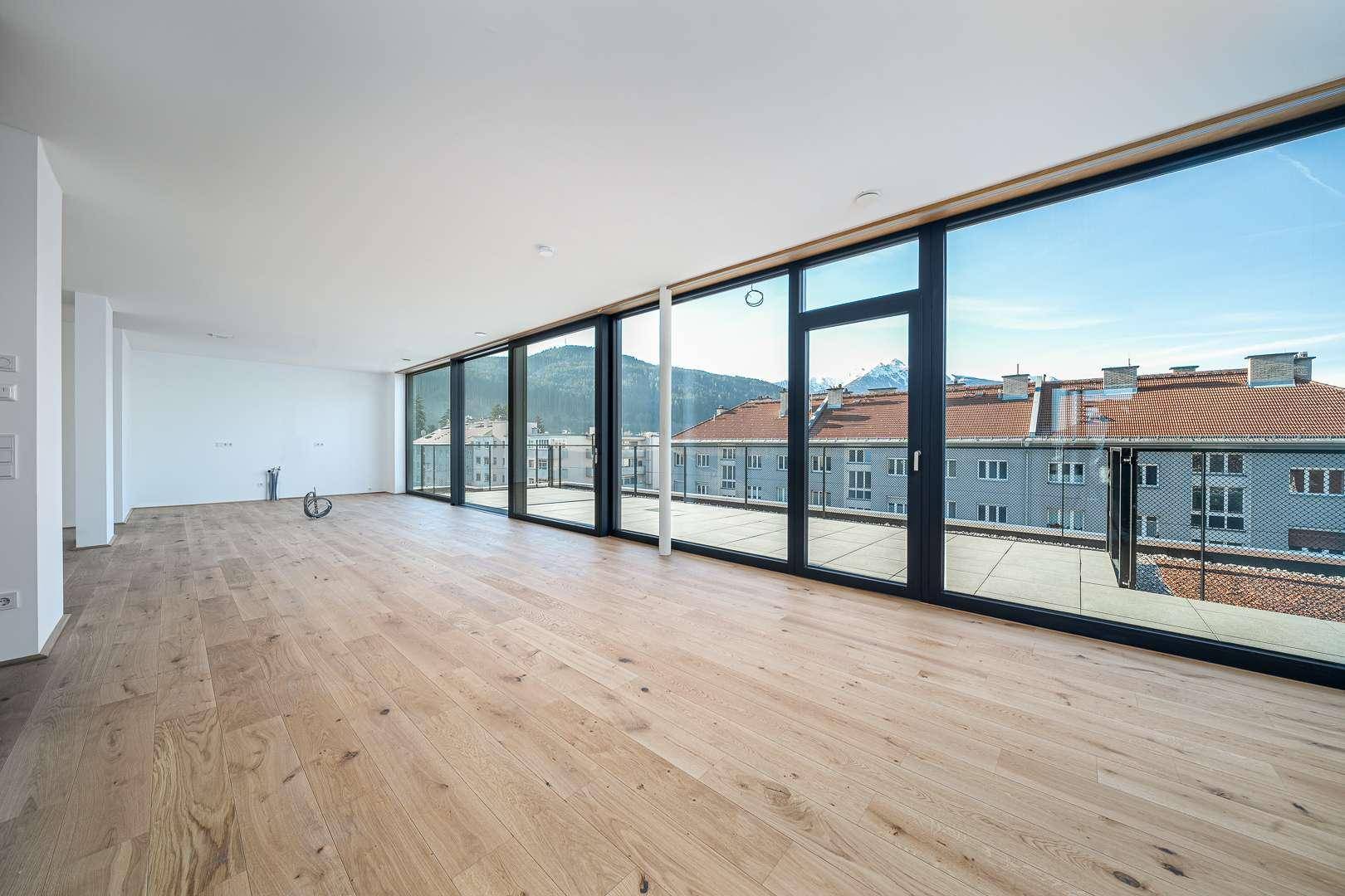 Heller Wohnbereich mit Holzboden und Zugang zu einer Terrasse, bietet weite Ausblicke.
