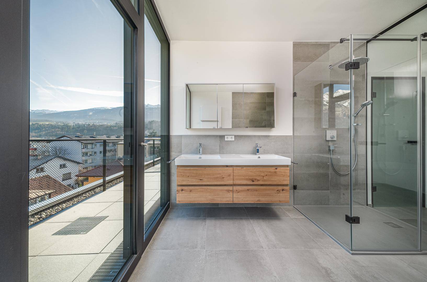 Helles Badezimmer mit Doppelwaschbecken, begehbarer Dusche und großen Fenstern mit Bergblick.