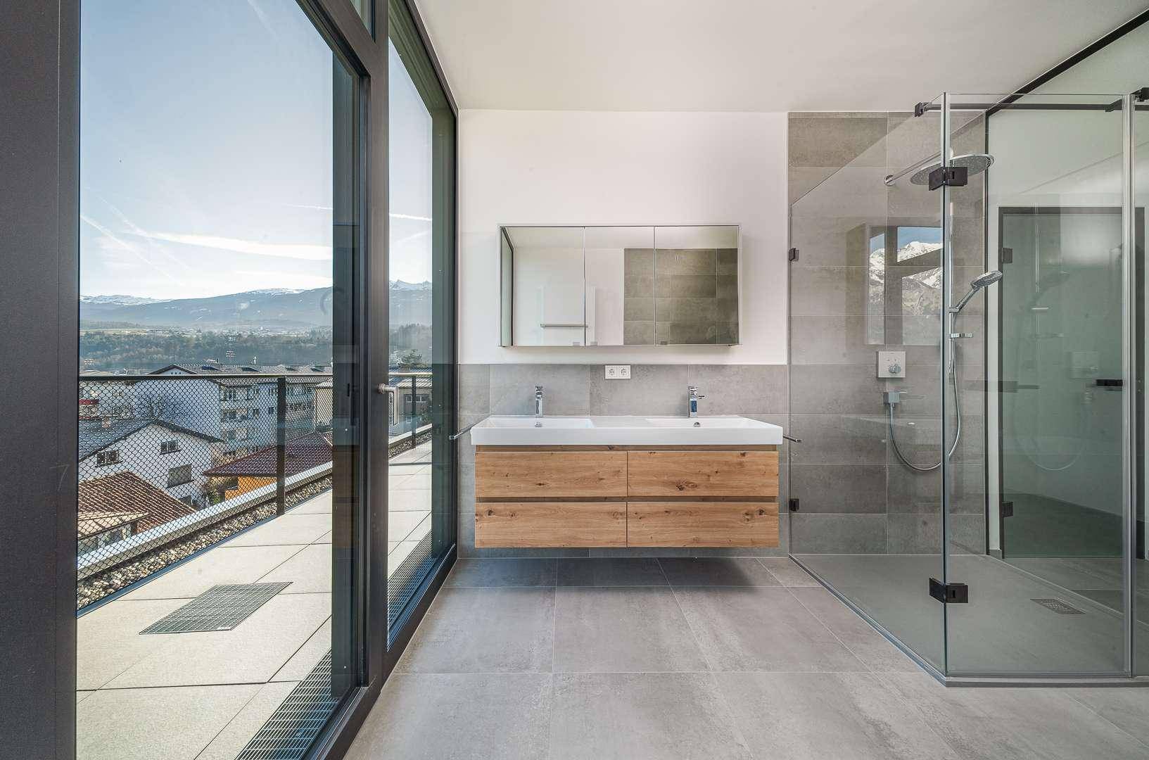 Elegantes Badezimmer mit Doppelwaschbecken, begehbarer Dusche und Zugang zur Terrasse.