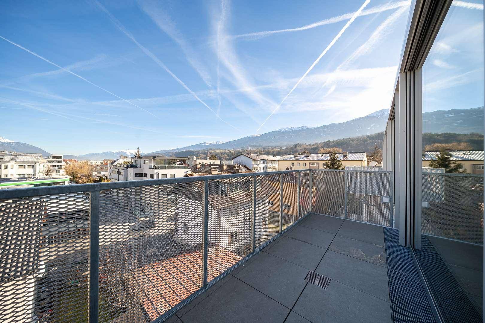 Balkon mit Metallgeländer und weitem Blick über die Stadt und die schneebedeckten Berge.