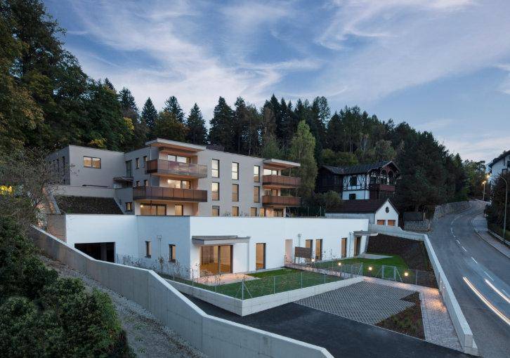 Moderne Wohnanlage am Hang mit Terrassen, Balkonen und Zufahrt.