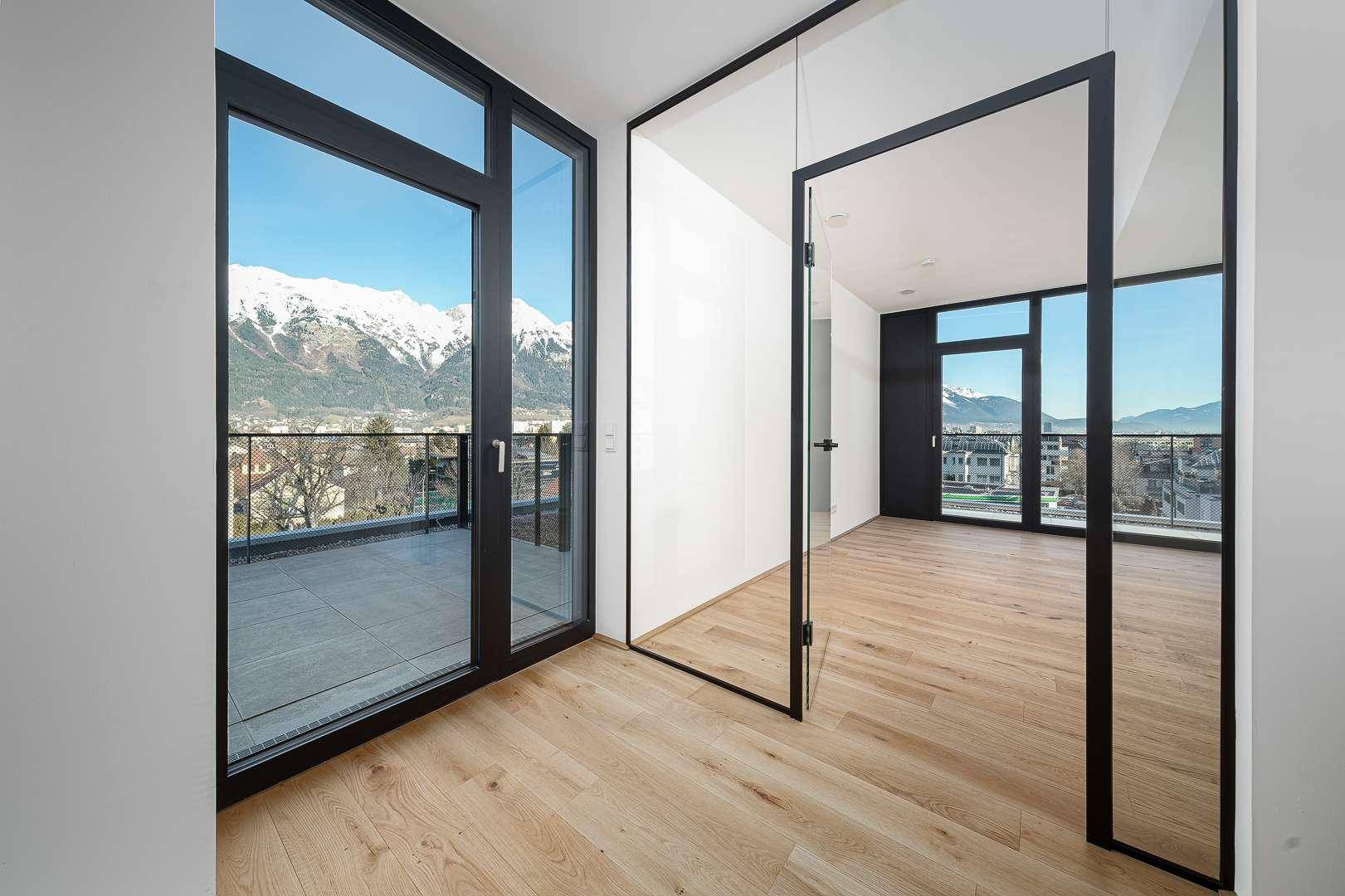 Heller Flurbereich mit Holzboden und modernen Glastüren, die zu weiteren Räumen führen.