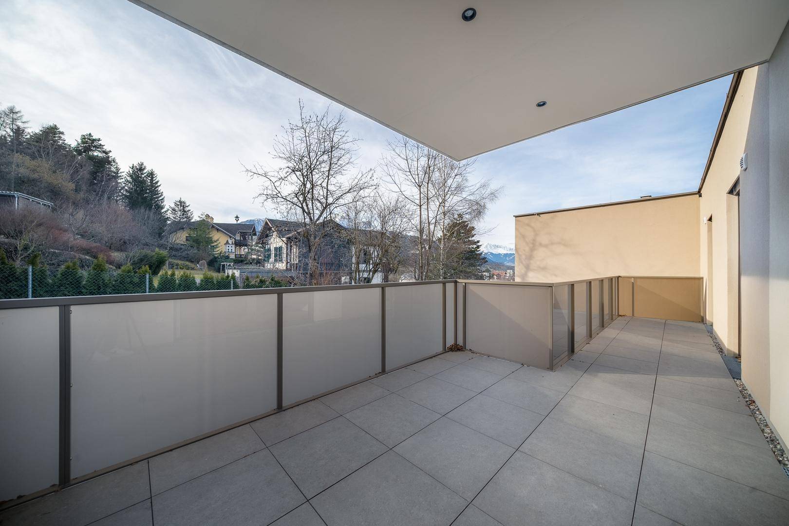 Geräumige Terrasse mit Fliesenboden und modernem Glasgeländer, bietet Bergblick.