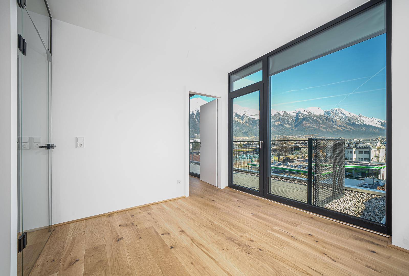 Geräumiges Schlafzimmer mit Holzboden und großen Fenstern, die einen weiten Blick auf die Berge bieten.