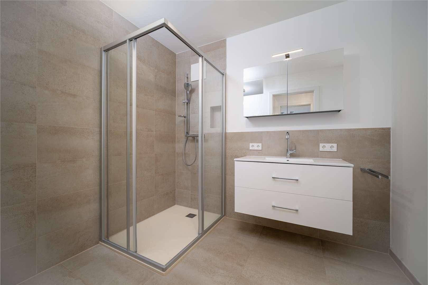 Modernes Badezimmer mit großer Duschkabine, schwebendem Waschtisch und Spiegelschrank.